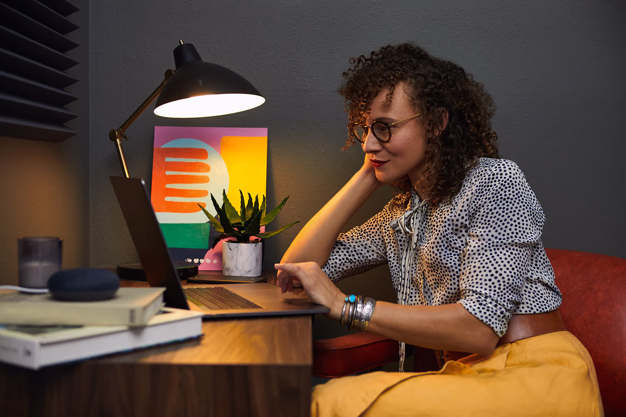A woman looking thoughtfully at a laptop in a home office